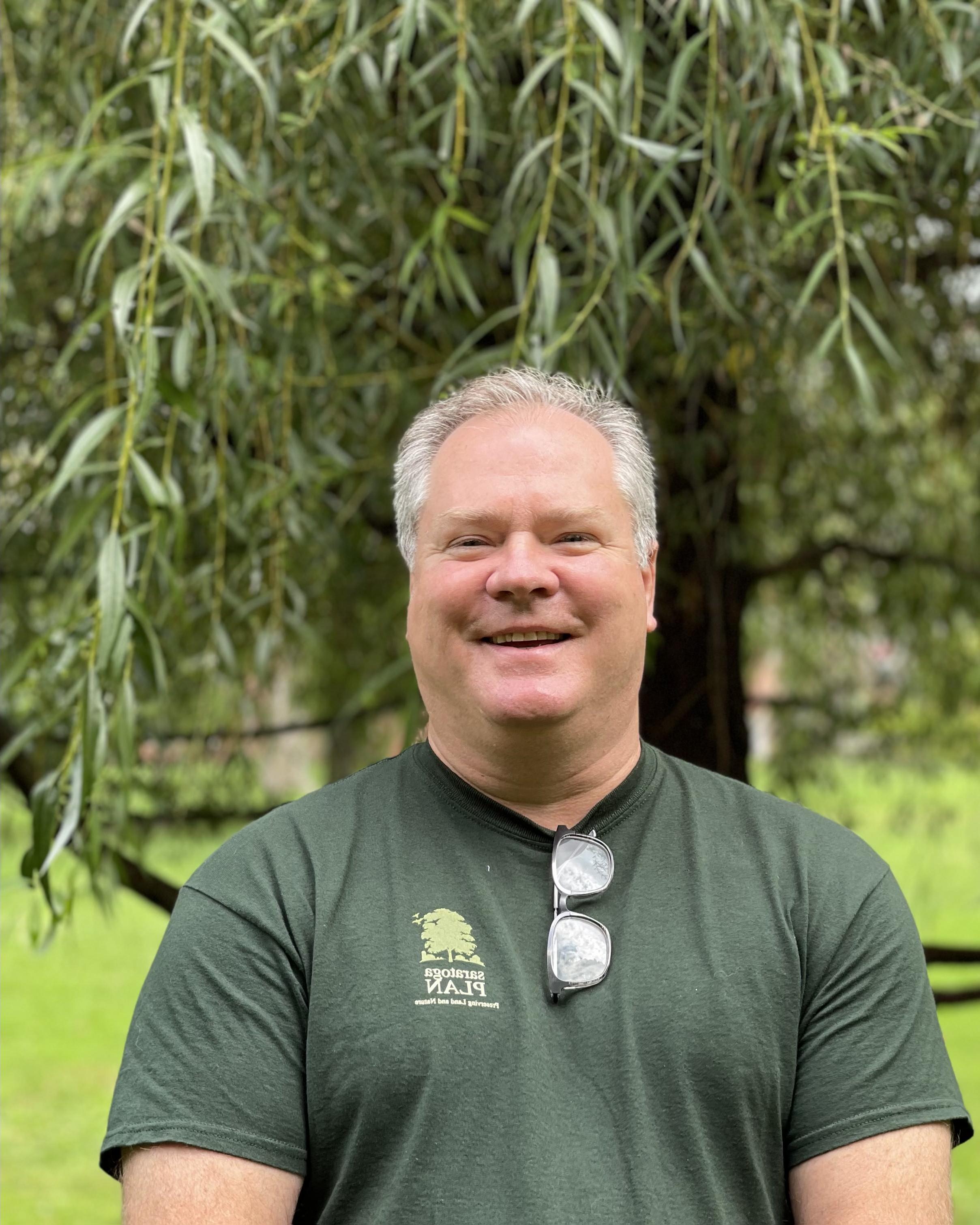 Rob smiles with lush greenery in the background